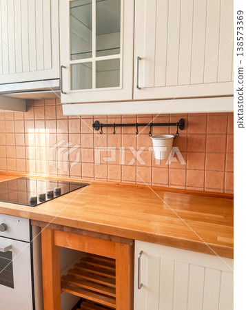 Bright kitchen interior with wooden countertop and tiled backsplash view. 138573369