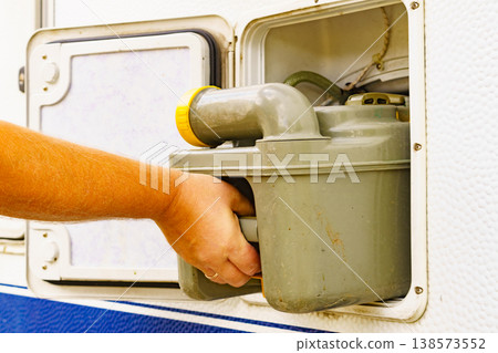 Man serving caravan, tank toilet cassette in dump station. Man serving caravan, tank toilet cassette in dump station. 138573552