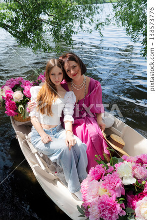 Mother and daughter on boat smiling. Joyful family bonding during lakeside boat trip. Cherished family moment captured as mother and daughter enjoy sunny lakeside adventure 138573776