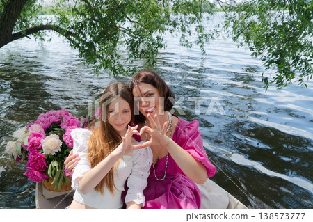 Mother and daughter on boat smiling. Joyful family bonding during lakeside boat trip. Cherished family moment captured as mother and daughter enjoy sunny lakeside adventure 138573777