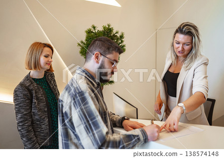Man and Two Women Standing at a Counter 138574148