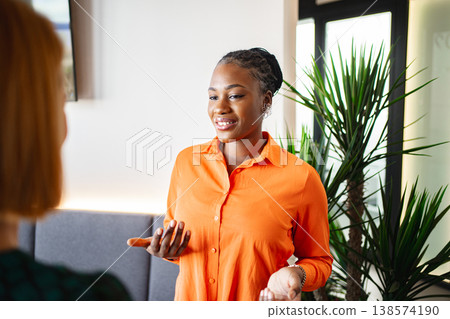 Women in Orange Shirts Having a Conversation 138574190