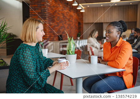 Two Women Sitting at a Table Talking Two Women Sitting at a Table Talking 138574219