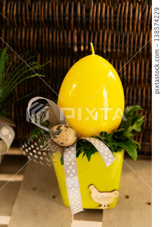 Cream egg in decorative pot with peacock feather, small wreath of boxwood, delicate ribbon and ceramic planter on rustic shelf, warm ambient light, handcrafted Easter table accent Cream egg in decorative pot with peacock feather, small wreath of boxwood, delicate ribbon and ceramic planter on rustic shelf, warm ambient light, handcrafted Easter table accent 138574229