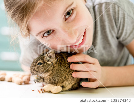 Portrait of young girl with degu squirrel and nuts, close-up. Portrait of young girl with degu squirrel and nuts, close-up. 138574343