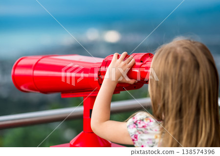 Young girl using a tower viewer to look at panoram of city Young girl using a tower viewer to look at panoram of city 138574396