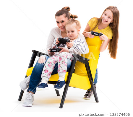 Family of three on leather yellow chair enjoying their time playing computer games with joystick 138574406