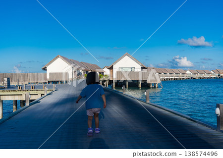 Japanese toddler walking among the overwater villas in the Maldives Japanese toddler walking among the overwater villas in the Maldives 138574496