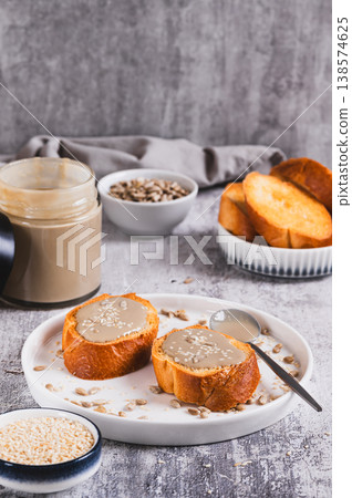 Urbech made from sesame and sunflower seeds on bread on a plate vertical view Urbech made from sesame and sunflower seeds on bread on a plate vertical view 138574625