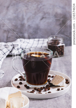 Black coffee with a piece of brie cheese in a glass on the table vertical view Black coffee with a piece of brie cheese in a glass on the table vertical view 138574634