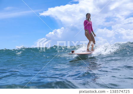 Lively Young Woman Guides Her Longboard Over Frothy Surf Under Blue Sky Lively Young Woman Guides Her Longboard Over Frothy Surf Under Blue Sky 138574725