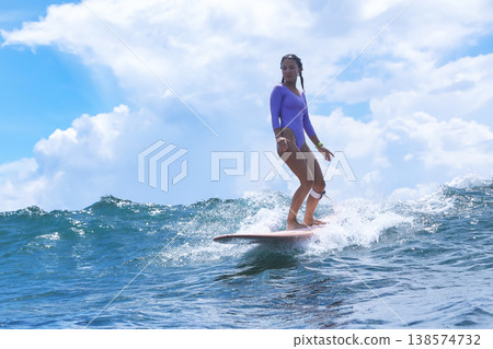 Teenage Girl Surfing Glossy Blue Crest With Bold Stances And Bright Sky Teenage Girl Surfing Glossy Blue Crest With Bold Stances And Bright Sky 138574732