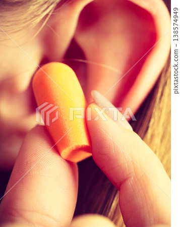 Woman putting earplugs Woman putting earplugs 138574949
