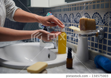 Middle-Aged Woman in Pajamas Performing Morning Skincare Routine at Bathroom Sink Middle-Aged Woman in Pajamas Performing Morning Skincare Routine at Bathroom Sink 138575003