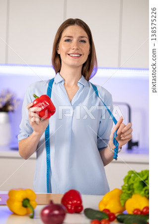 Smiling young woman near the table full of vegetables in the kitchen 138575226