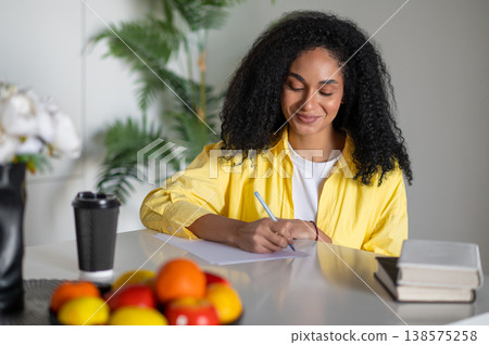 Beautiful young woman sitting at the table and looking inspired and excited Beautiful young woman sitting at the table and looking inspired and excited 138575258