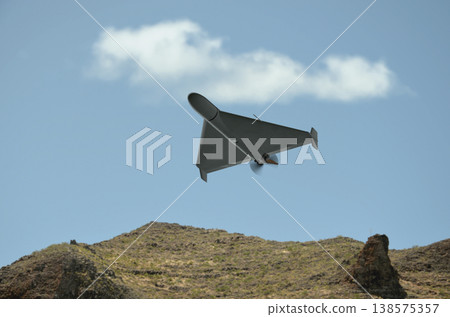 Kamikaze combat drone flies in the sky over mountainous landscape in military conflict conditions Kamikaze combat drone flies in the sky over mountainous landscape in military conflict conditions 138575357
