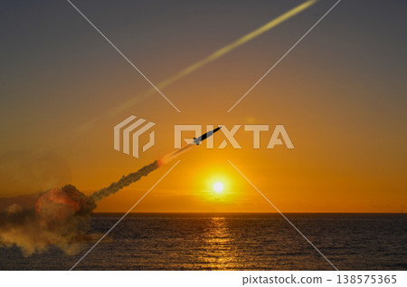 Military missile with smoke trail rises into sky at sunset over sea in conflict conditions 138575365