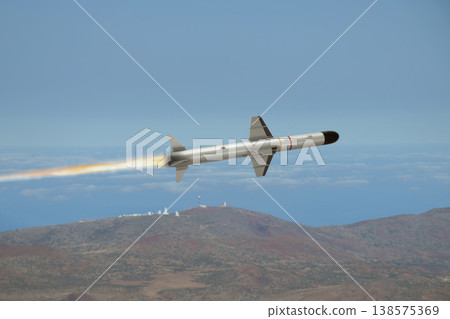 Military missile in flight over clouds and mountainous region Military missile in flight over clouds and mountainous region 138575369