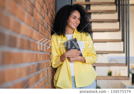 Cute long-haired smiling woman in yellow jacket with a book in hands 138575574