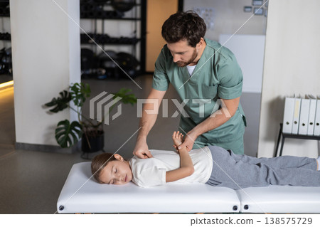Male doctor talking to patient while examining shoulder 138575729