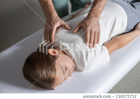 Specialist performing manual back therapy on young patient Specialist performing manual back therapy on young patient 138575732