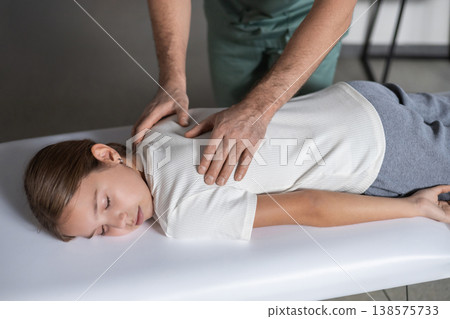 Physiotherapist massaging child spine in medical office 138575733