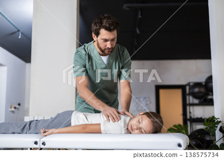 Close up of hands performing back therapy on child 138575734