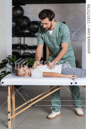 Specialist massaging child back during recovery session Specialist massaging child back during recovery session 138575736