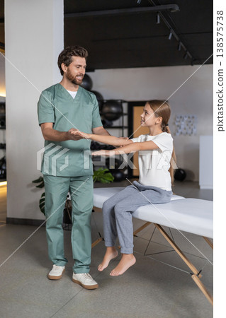 Detail of specialist assisting girl with arm movements 138575738