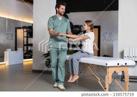 Professional therapist guiding girl during arm training Professional therapist guiding girl during arm training 138575739