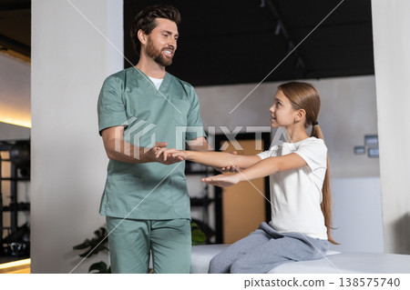 Specialist assisting child with arm stretching exercises Specialist assisting child with arm stretching exercises 138575740