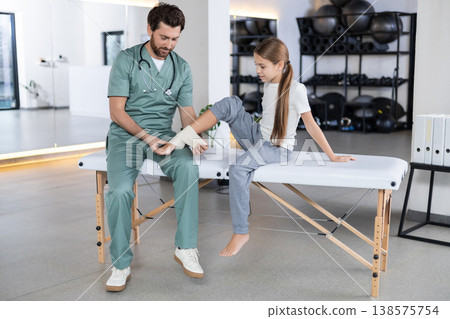 Close up of therapist hands wrapping girl leg Close up of therapist hands wrapping girl leg 138575754