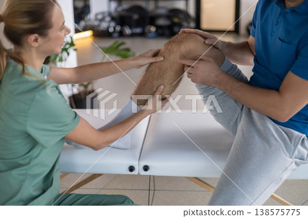 Close up of therapist hands examining patient knee Close up of therapist hands examining patient knee 138575775