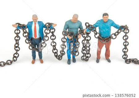Miniature people holding chains in a creative display showcasing struggle and connection among Miniature people holding chains in a creative display showcasing struggle and connection among 138576052