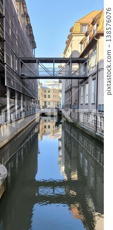 A metal bridge-crossing between buildings over a water channel A metal bridge-crossing between buildings over a water channel 138576076