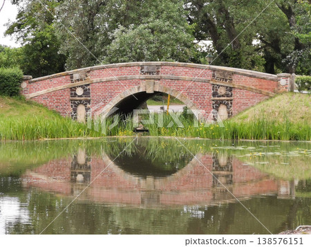 The brick bridge is reflected in the pond located in the green park The brick bridge is reflected in the pond located in the green park 138576151