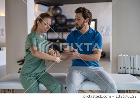 Physiotherapist wrapping bandage on patient wrist Physiotherapist wrapping bandage on patient wrist 138576152