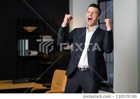 Happy male executive raising hands and celebrating win Happy male executive raising hands and celebrating win 138576190