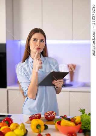 Young woman cooking in the kitchen and looking for a recipe online Young woman cooking in the kitchen and looking for a recipe online 138576256