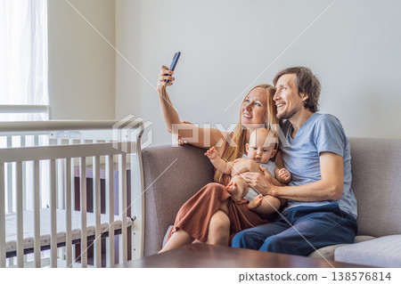 Mother and father sitting on sofa hugging their baby at home. Loving parents embracing newborn with tenderness and care. Family bonding, parenthood, warmth and emotional connection concept Mother and father sitting on sofa hugging their baby at home. Loving parents embracing newborn with tenderness and care. Family bonding, parenthood, warmth and emotional connection concept 138576814