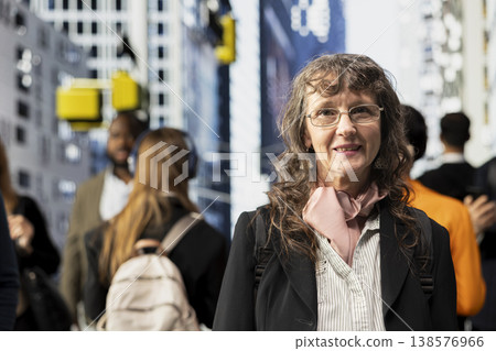 Mature old woman crossing the street in busy city center area, waiting at the red light with multiple diverse pedestrians. Active senior female walking next to urban street people. Mature old woman crossing the street in busy city center area, waiting at the red light with multiple diverse pedestrians. Active senior female walking next to urban street people. 138576966