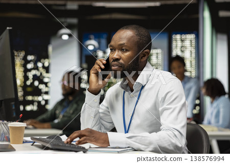 African american business analyst making a phone call late at night to ensure upcoming schedule, discussing with his partner on telephone line. Busy manager showing professionalism. 138576994