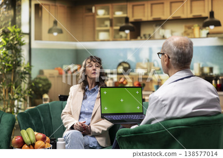 Mockup display on laptop held by senior medic during home care services, conducting healthcare routine exam for old woman. Monitoring vital signs and giving supplements for longevity. Mockup display on laptop held by senior medic during home care services, conducting healthcare routine exam for old woman. Monitoring vital signs and giving supplements for longevity. 138577014