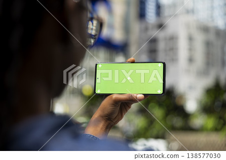 Isolated screen smartphone in landscape mode, watching movies and relaxed person on park bench. Consuming entertainment, mockup mobile phone close up and woman enjoying nice day outside 138577030
