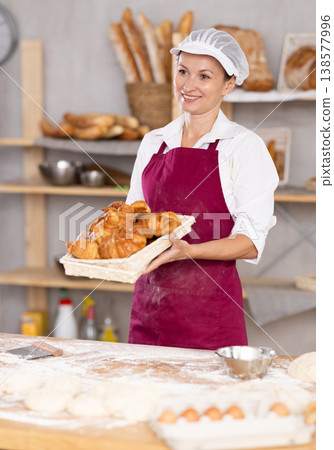 Adult female baker with basket of croissants Adult female baker with basket of croissants 138577996