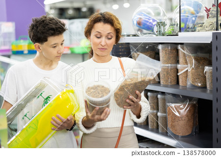 Family mom and son in animal goods store examines packaging of dry food for turtles Family mom and son in animal goods store examines packaging of dry food for turtles 138578000