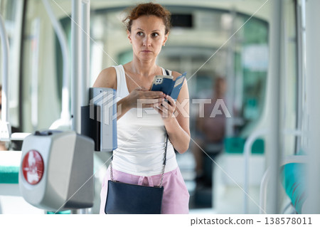 Adult woman standing in train car with phone 138578011