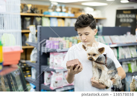 Teenager with Yorkshire terrier choosing dry dog food in pet store Teenager with Yorkshire terrier choosing dry dog food in pet store 138578038