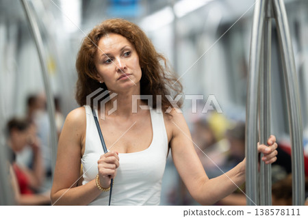 Portrait of woman passenger standing inside train at metro wagon Portrait of woman passenger standing inside train at metro wagon 138578111